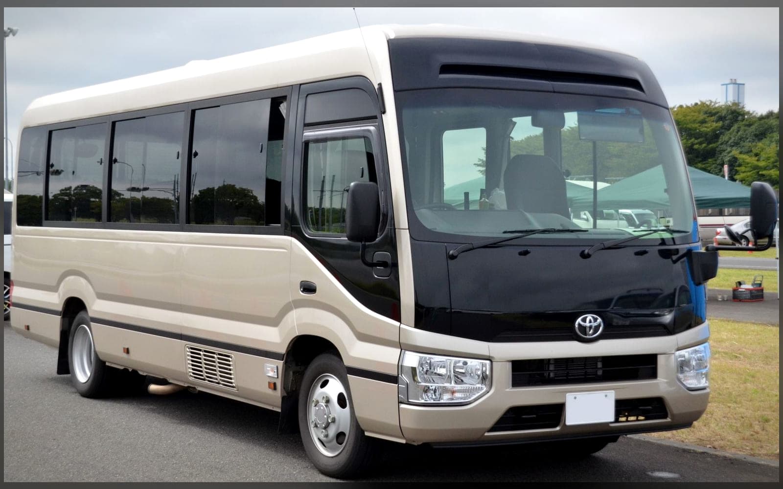 White Toyota Coaster minibus, front three-quarter view