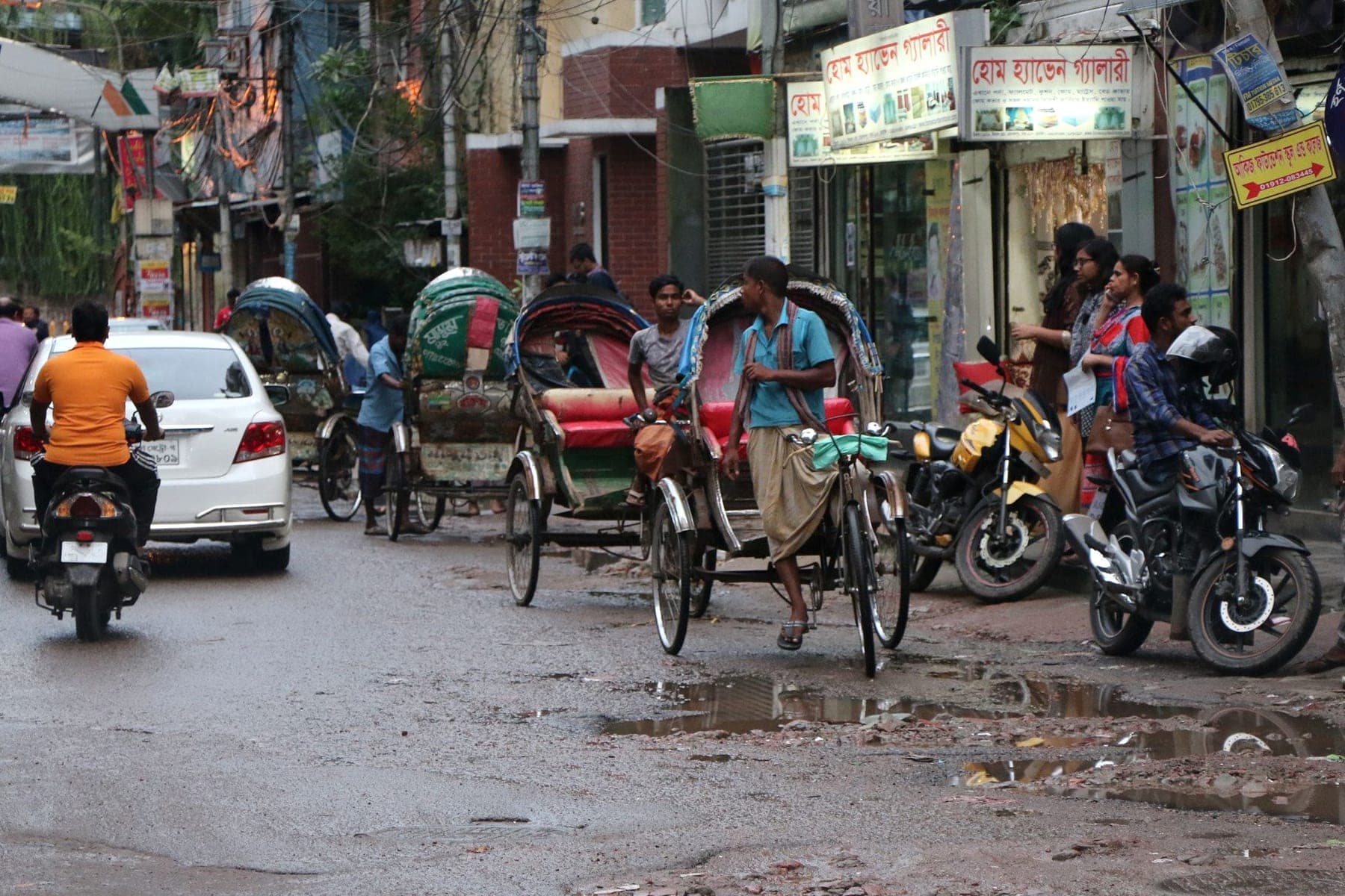 A Dhaka street with rickshaws, motorcycles and shopfronts